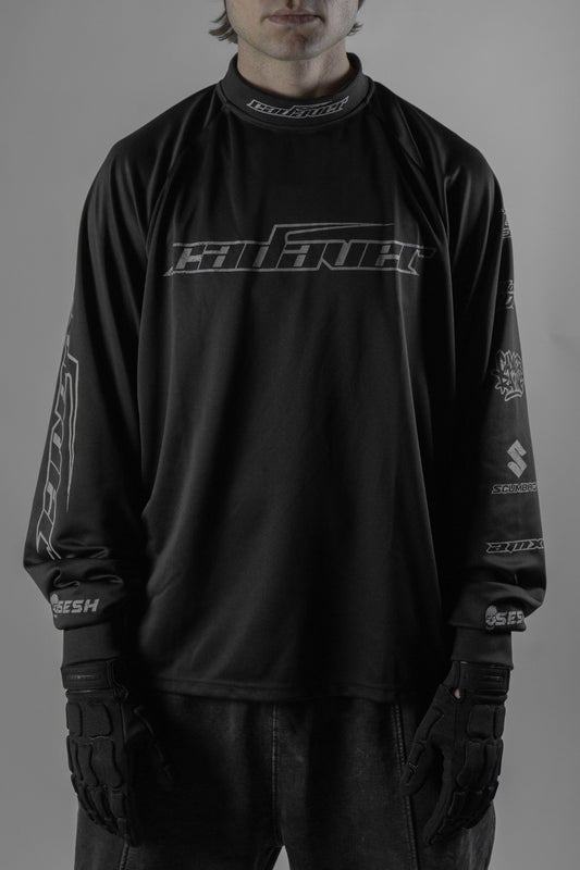 Person wearing a black long-sleeve shirt with logos on a gray background